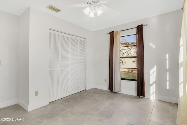 unfurnished bedroom featuring light tile patterned floors, a closet, visible vents, a ceiling fan, and baseboards