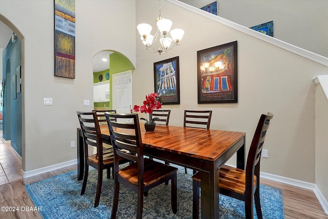 dining room featuring a towering ceiling, wood-type flooring, and a chandelier