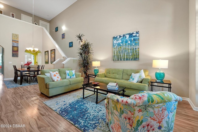 living room featuring high vaulted ceiling, an inviting chandelier, and hardwood / wood-style floors