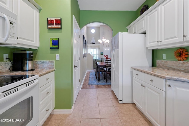 kitchen with light tile patterned flooring, white appliances, a notable chandelier, white cabinets, and pendant lighting