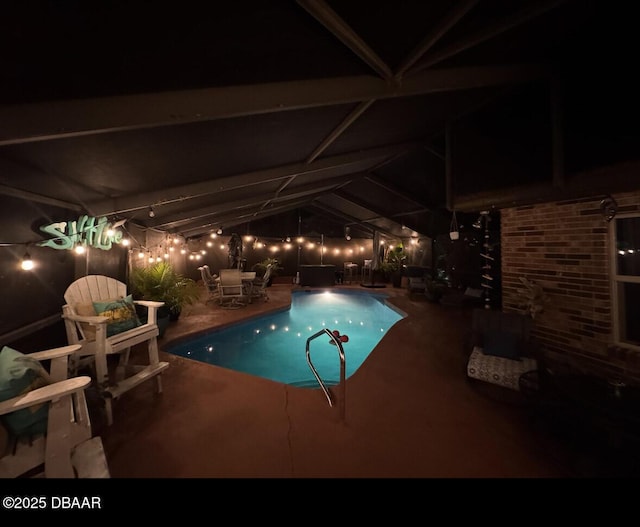 pool at night with an outdoor pool and a patio area