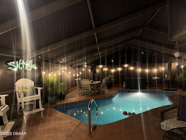 pool at night featuring a patio area and an indoor pool