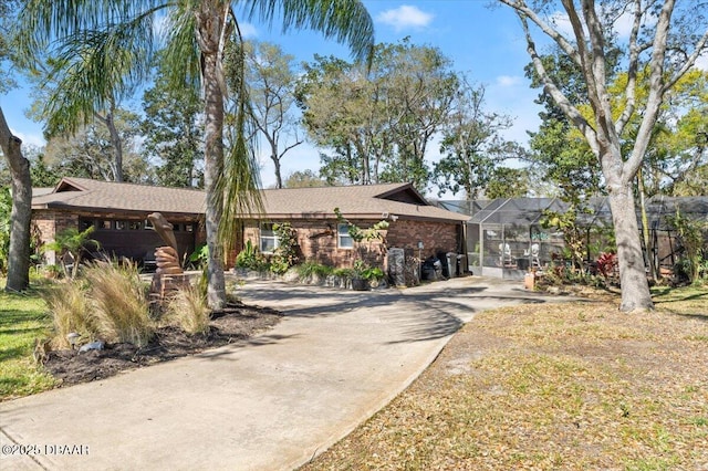 ranch-style home featuring a lanai, concrete driveway, and brick siding