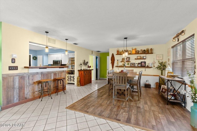 dining room with light tile patterned flooring, visible vents, and a textured ceiling