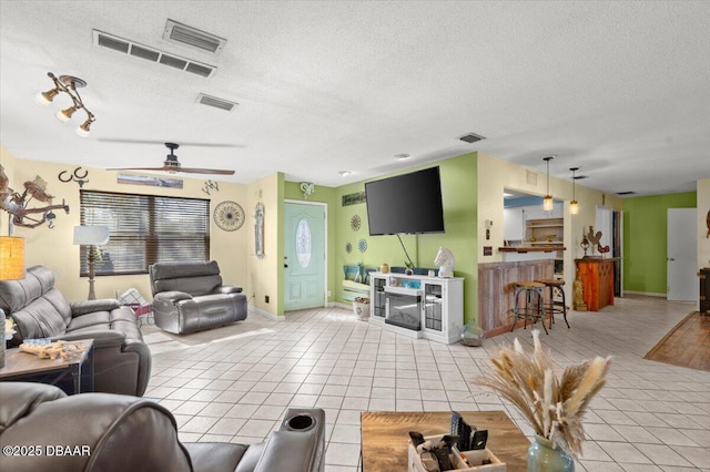 living room featuring light tile patterned floors, visible vents, and a textured ceiling