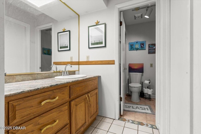 bathroom featuring vanity, tile patterned floors, and toilet