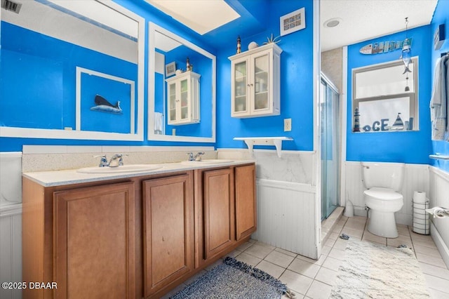 bathroom featuring a sink, visible vents, a shower stall, and wainscoting