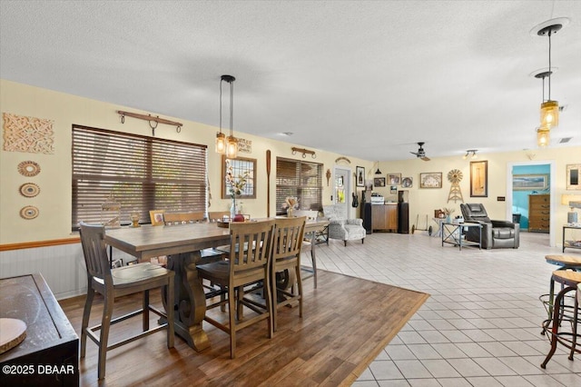 dining space with tile patterned flooring, ceiling fan, and a textured ceiling