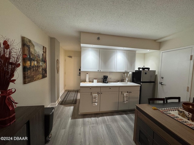 kitchen with stainless steel fridge, a textured ceiling, light hardwood / wood-style flooring, and sink