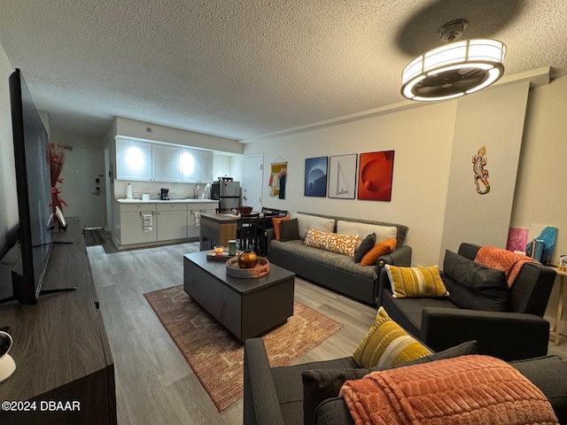 living room featuring light wood-type flooring and a textured ceiling