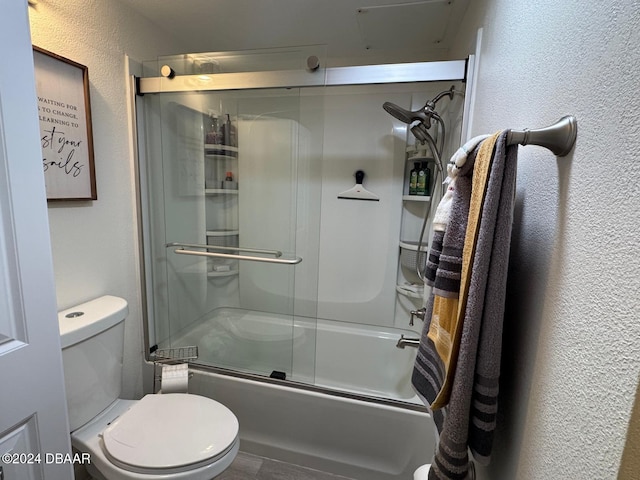 bathroom with toilet and combined bath / shower with glass door