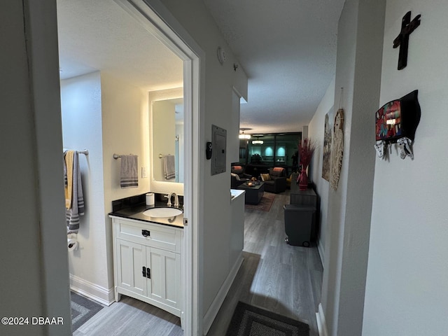 corridor with a textured ceiling, dark hardwood / wood-style flooring, and sink