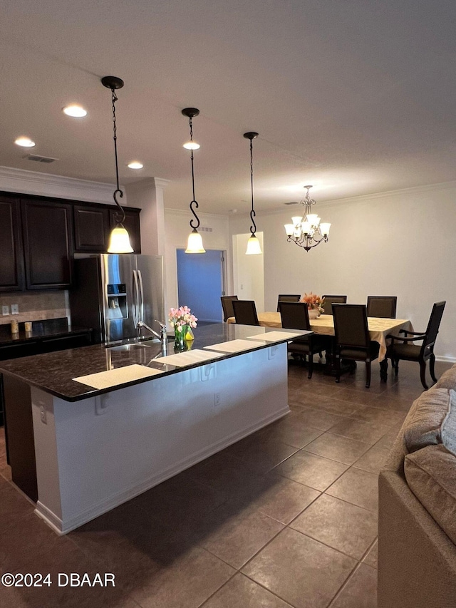 kitchen with tile patterned floors, ornamental molding, decorative light fixtures, a center island with sink, and stainless steel fridge with ice dispenser