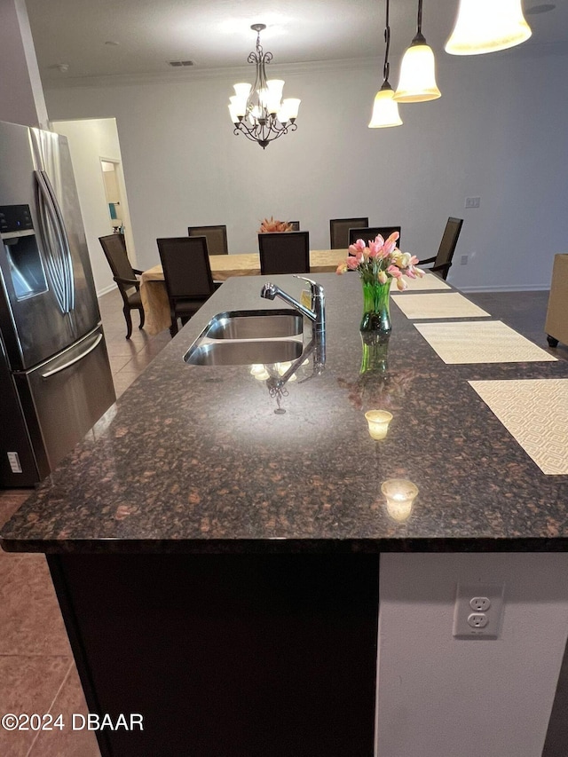 kitchen featuring stainless steel fridge, a kitchen island with sink, pendant lighting, and sink