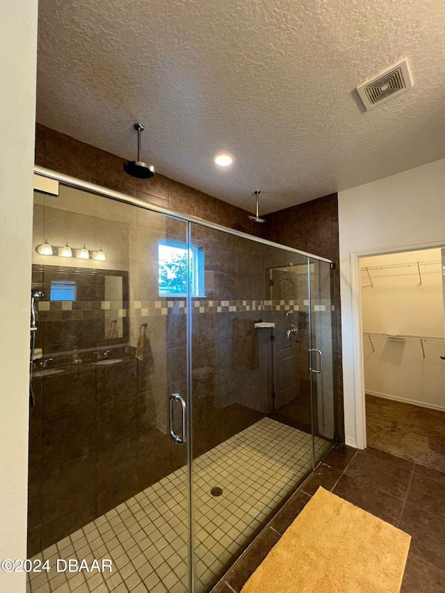 bathroom featuring tile patterned floors, an enclosed shower, and a textured ceiling