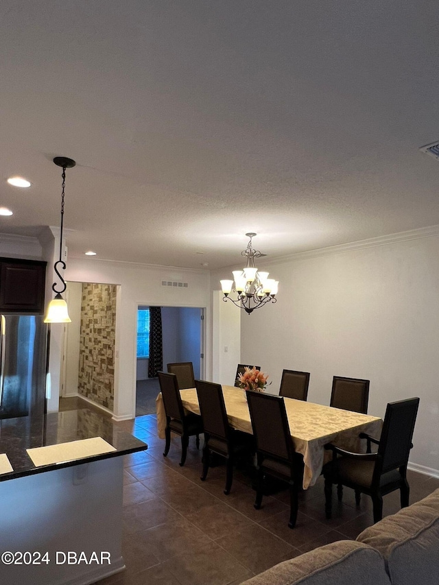 dining space featuring dark tile patterned floors, crown molding, and a chandelier