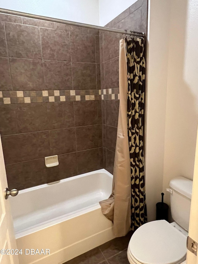 bathroom featuring tile patterned floors, toilet, and shower / bathtub combination with curtain