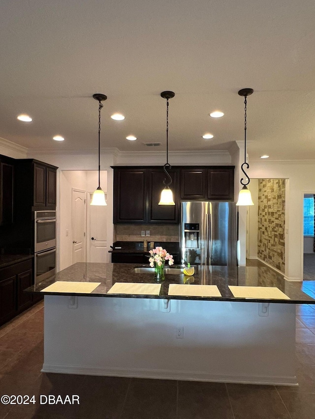 kitchen with stainless steel appliances, pendant lighting, a kitchen island with sink, dark brown cabinets, and ornamental molding