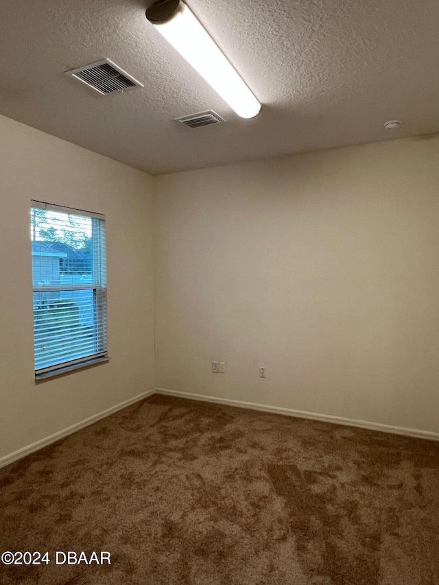 carpeted spare room featuring a textured ceiling