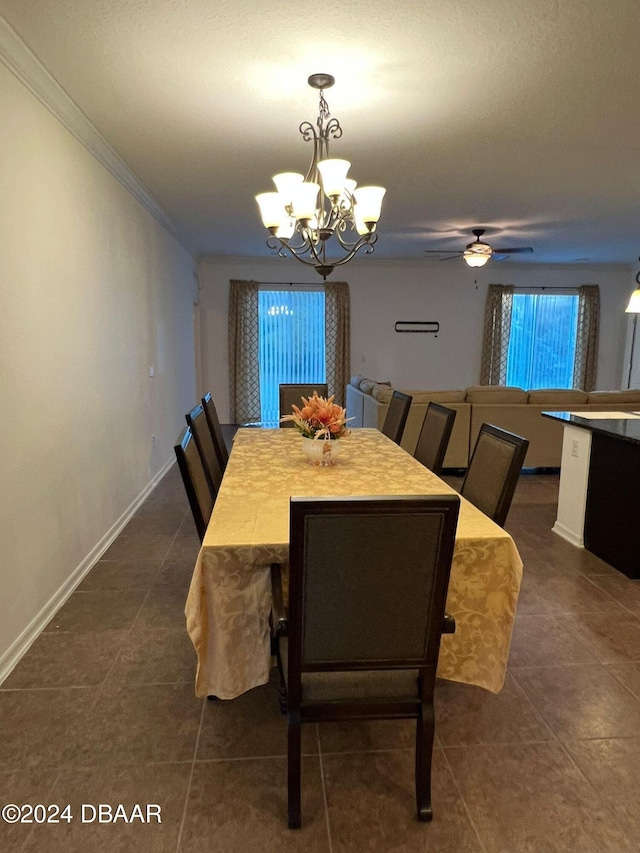 dining space with ceiling fan with notable chandelier, dark tile patterned floors, and ornamental molding