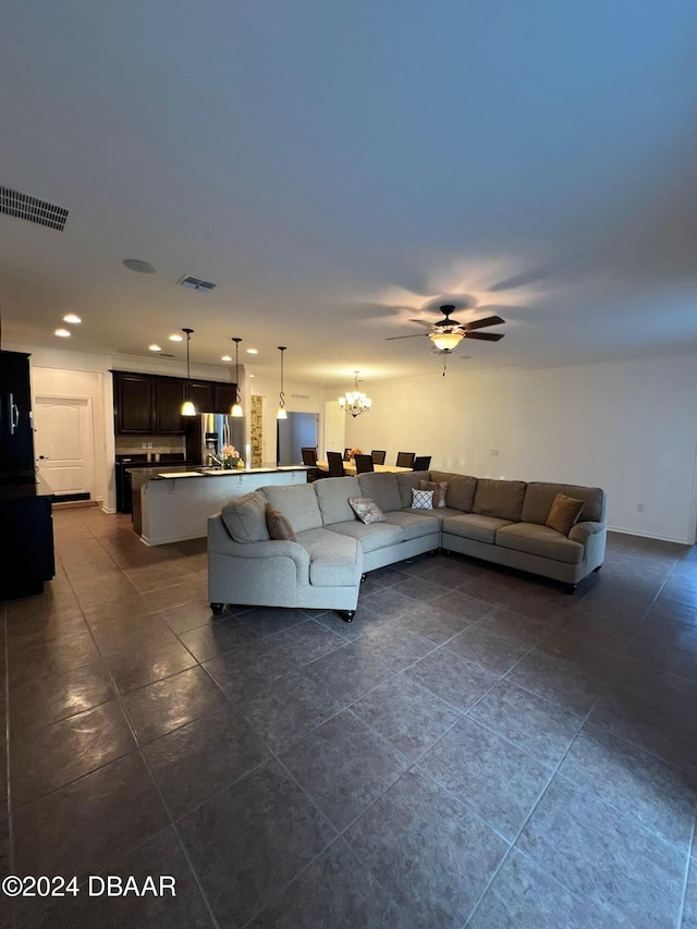 living room featuring dark tile patterned flooring and ceiling fan with notable chandelier