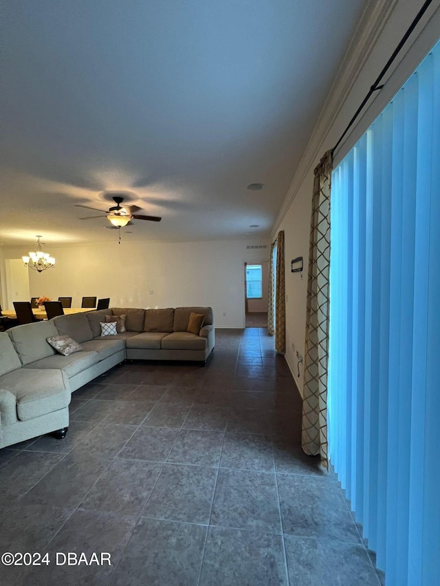 tiled living room with ceiling fan with notable chandelier and crown molding