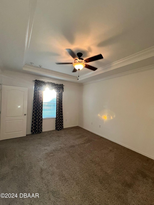 empty room with a tray ceiling, ceiling fan, crown molding, and carpet flooring