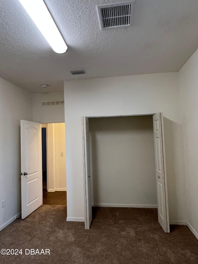 unfurnished bedroom featuring dark colored carpet and a textured ceiling