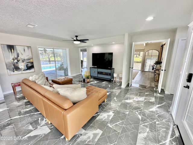 living room featuring baseboards, a textured ceiling, and ceiling fan