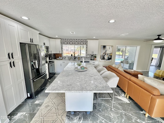 kitchen featuring open floor plan, a breakfast bar area, a kitchen island, and stainless steel appliances
