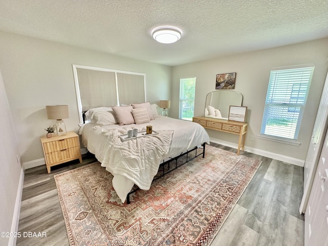bedroom with a textured ceiling, multiple windows, and wood finished floors
