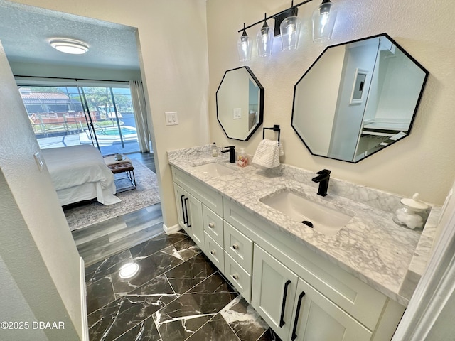 ensuite bathroom with a sink, connected bathroom, double vanity, and marble finish floor