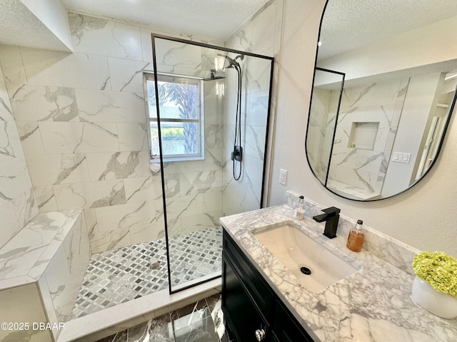 bathroom featuring a marble finish shower, vanity, a textured ceiling, and marble finish floor