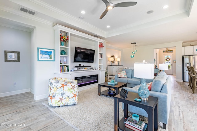 living room with ornamental molding, light hardwood / wood-style flooring, ceiling fan, and a raised ceiling