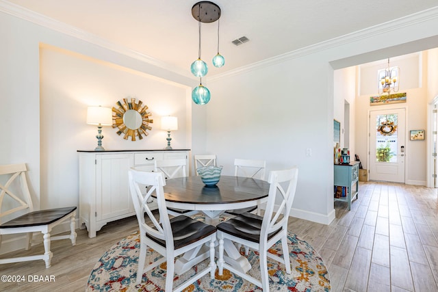 dining area with light hardwood / wood-style flooring, a notable chandelier, and crown molding