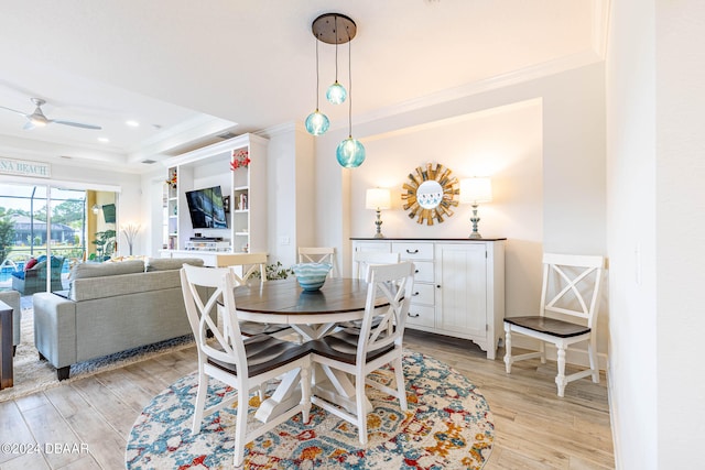 dining area with ceiling fan, a tray ceiling, light hardwood / wood-style floors, and crown molding