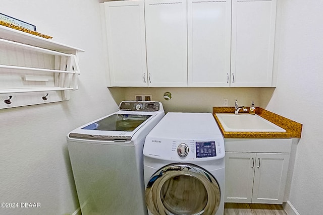 washroom featuring cabinets, hardwood / wood-style flooring, sink, and independent washer and dryer