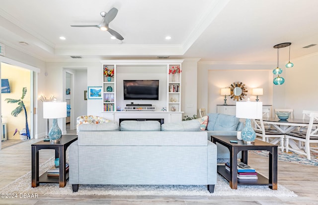 living room with light wood-type flooring, a raised ceiling, ceiling fan, and crown molding