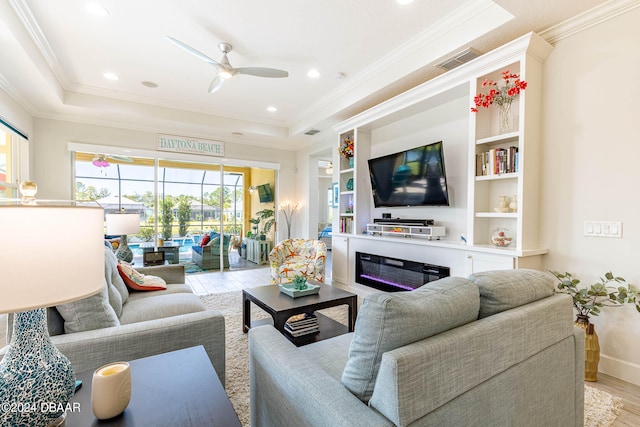 living room featuring ceiling fan, a raised ceiling, light hardwood / wood-style flooring, and crown molding