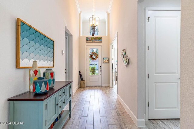 1078 Castaway Ct, Daytona Beach, FL 32124 - foyer featuring a chandelier, light wood-style flooring, crown molding, baseboards, and a towering ceiling