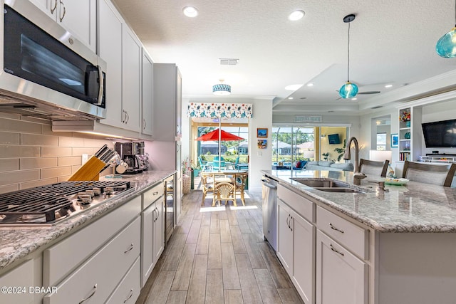 1078 Castaway Ct, Daytona Beach, FL 32124 - kitchen featuring appliances with stainless steel finishes, a sink, open floor plan, wood finished floors, and crown molding