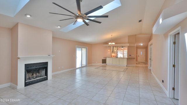 unfurnished living room with light tile patterned floors, ceiling fan with notable chandelier, and vaulted ceiling with skylight