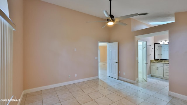 unfurnished bedroom featuring ceiling fan, sink, high vaulted ceiling, ensuite bathroom, and light tile patterned floors