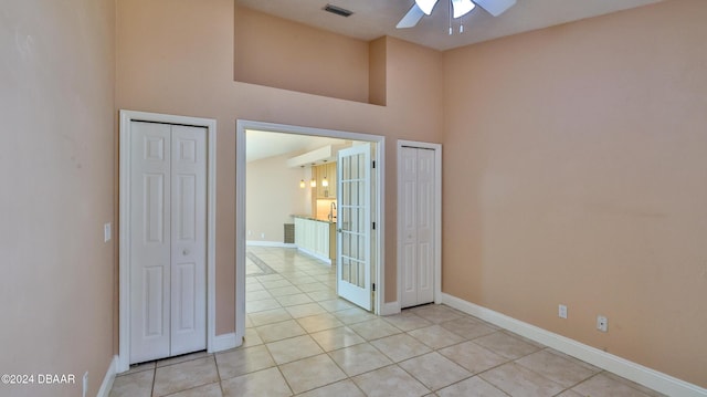 unfurnished room featuring ceiling fan, light tile patterned flooring, and a high ceiling