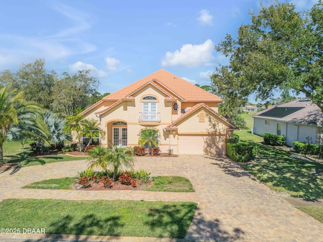 mediterranean / spanish-style house featuring stucco siding, a tile roof, decorative driveway, french doors, and a front yard