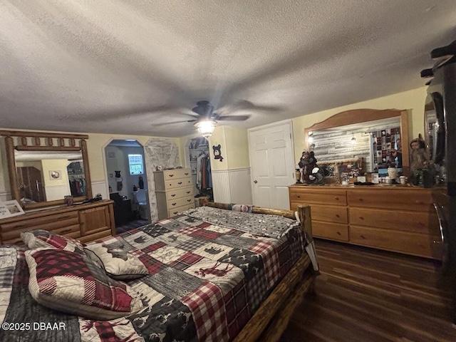 17531 NE 139th Ave, Fort Mccoy, FL 32134 - bedroom featuring a textured ceiling, arched walkways, a wainscoted wall, dark wood-style floors, and a ceiling fan