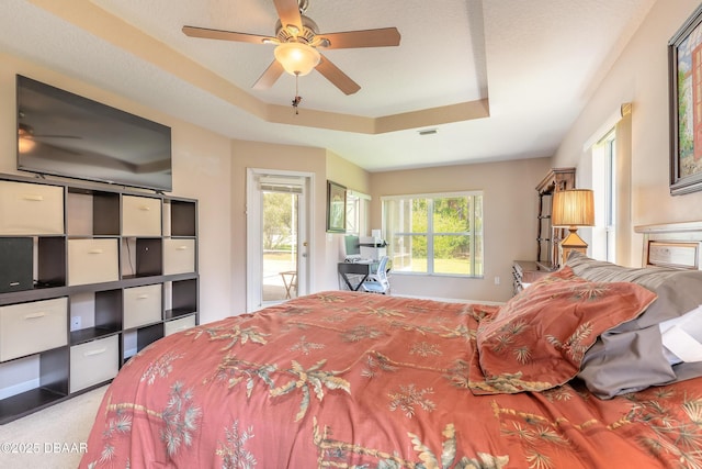 bedroom with carpet, visible vents, a ceiling fan, and a raised ceiling