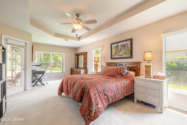 bedroom with baseboards, a ceiling fan, carpet floors, a tray ceiling, and access to exterior