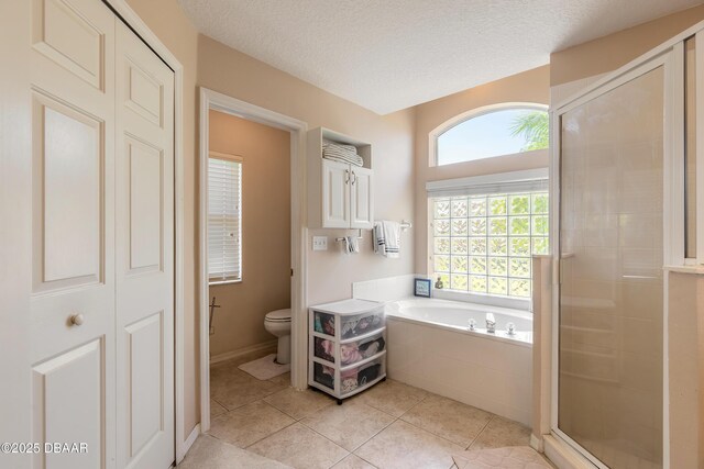 bathroom featuring tile patterned floors, toilet, a bath, and a stall shower