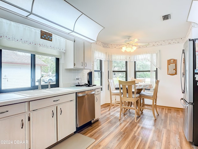 kitchen featuring appliances with stainless steel finishes, light hardwood / wood-style flooring, white cabinetry, and plenty of natural light